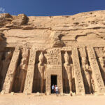 古代エジプト神殿建築の最高傑作といわれるアブ・シンベル神殿は、ナイル川にせり出した岩山を掘削して造られた岩窟神殿で、神殿正面には高さ約22mもあるラムセス2世の座像が4体並び、足元には彼の母や王妃、息子、娘などの小さな立像があります。